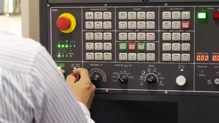 CNC operator adjusting machine settings on a control panel