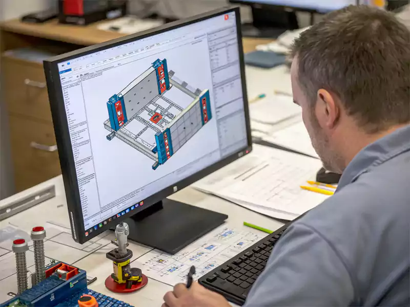 An engineer's computer screen showing a detailed CAD design of a custom jig