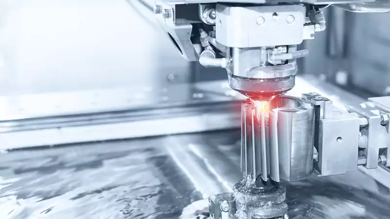 A wire EDM machine cutting a precise gear shape out of a block of hardened steel