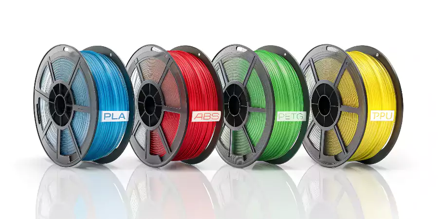 A lineup of different colored spools of FDM filament, labeled PLA, ABS, PETG, and TPU